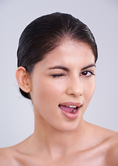 Image showing Happy woman, portrait and wink with skincare for beauty, cosmetics or facial treatment on a white studio background. Face of female person, brunette or model with smile in satisfaction for makeup