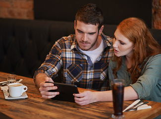 Image showing Couple, browsing and checking menu with tablet for dinner date, streaming or review at indoor restaurant. Young man and woman chilling or relax with technology for social media at cafe or coffee shop