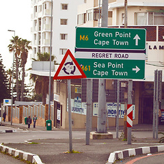 Image showing Road sign, intersection and circle in city with arrow for grammar, mistake or comic text for driving in neighborhood. Buildings, error and funny signage with joke, regret and warning in Cape Town