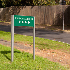 Image showing Road sign, arrow and outdoor for direction in neighborhood to search for houses, address and funny joke. Green board, signage and pointing on grass, lawn and comic text with mistake, error or humor
