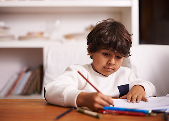 Image showing Student, child and home for writing, learning or education in school books with color or drawing. Mexican boy or kid with pencil for language development, homework and creativity or solution at table
