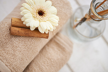 Image showing Flower, cinnamon stick and towels for aromatherapy at spa, incense and spices for holistic healing. Top of tools for treatment, stress relief and self care with natural ingredients and glass bottle