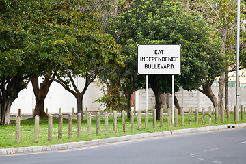Image showing Road sign, destination and signage in street for location with place notification and white square outdoor. Attention, public notice and signpost for navigation, alert message and symbol with trees