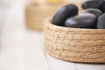Image showing Stone, massage and closeup on basket in spa for luxury service in hospitality at hotel on holiday or vacation. Rocks, container and object for wellness treatment on table or detail of pebble