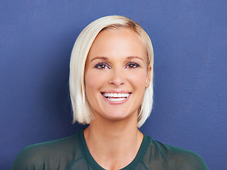 Image showing Portrait, beauty and smile of woman in studio for fashion isolated on blue background. Face, blonde or happy female person in casual clothes, makeup cosmetics or laughing on a backdrop in Switzerland