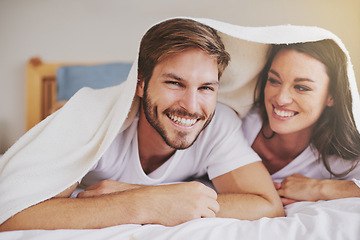 Image showing Smile, love and couple with blanket for relaxing, bonding and resting on bed together at home. Happy, romantic and young man and woman laying with duvet in bedroom at hotel, house or apartment.