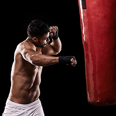 Image showing Boxing, man and workout in studio with punching bag for training, exercise or competition fight with fitness. Athlete, boxer and power for martial arts with performance or topless on black background