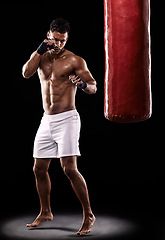 Image showing Fitness, punching bag and man boxer in studio for body, training or performance on black background. Fighter, impact and topless male athlete with martial arts, mama or kickboxing match practice