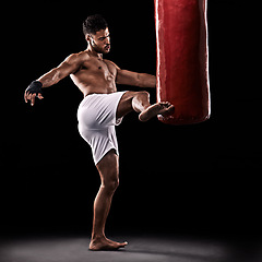 Image showing Kickboxing, man and training in studio with punching bag for workout, exercise or competition fight with fitness. Athlete, boxer and strong for martial arts with power and topless on black background