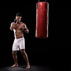 Image showing Ready, boxer and man with punching bag in studio with gloves for training with strength and muscle. Adult, athlete and male person in dark background, healthy and power with body, serious and sport