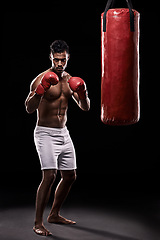 Image showing Portrait, boxing bag and gloves for male boxer, studio and athlete on black background. Dark, training and combat sports or MMA for man model, workout, muscle and impact activity for martial arts