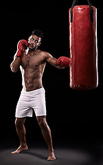 Image showing Studio, athlete and man with punching bag and gloves for training with strength and muscle. Adult, boxer and male person in dark background, healthy and power with body for sport and serious for job