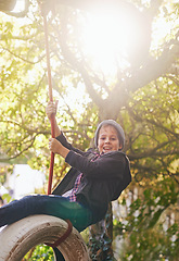 Image showing Boy, tyre swing and portrait outdoor with happiness, playing and countryside vacation in summer. Child, face and diy adventure playground in garden of home with sunlight, trees and excited in nature