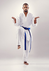 Image showing Studio, karate and African man training to improve physical health with fast and effective technique. White background, male person and adult with disciple of martial arts, sport and blue belt
