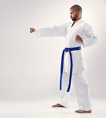 Image showing Studio, karate and African man training technique for physical health of blue belt instructor. White background, male person and adult with disciple of martial arts, sport and fist for combat