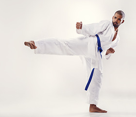 Image showing Man, kick and karate fighter in studio, fitness and martial arts on white background. Black male person, athlete and blue belt for taekwondo, discipline and warrior ready for self defense or battle