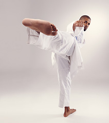 Image showing Karate, exercise and man kick in portrait on studio, white background or mockup of martial arts. Serious, warrior and training to fight with foot and punch fist with power in competition for sport