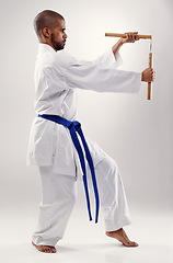 Image showing Karate, fight and man with nunchaku in martial arts, studio or training with weapon for defence on white background. Nunchucks, exercise and fighting with equipment in sport with skill and power