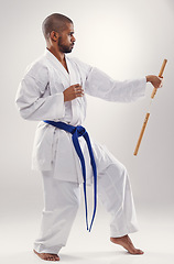 Image showing Nunchaku, karate and man in martial arts fight with weapon in training for defence in white background of studio. Nunchucks, exercise and fighting with equipment in sport with skill and power in gym