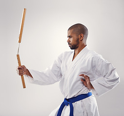 Image showing Nunchaku, karate and man in martial arts fight with weapon in training for defence in white background of studio. Nunchucks, exercise and fighting with equipment in sport or gym with creative skill