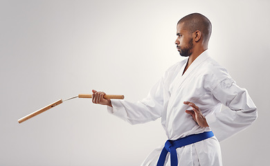 Image showing Nunchucks, karate and man in martial arts fight with weapon in training for defence in white background of studio. Nunchaku, exercise and fighting with equipment in sport with skill and power in club