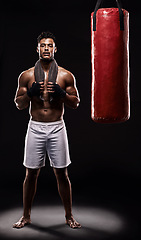 Image showing Portrait, boxing bag and male boxer for break, studio and athlete on black background. Dark, training and combat sports or MMA for man model, workout, muscle and impact activity for martial arts