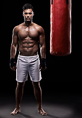 Image showing Studio, boxer and portrait of man, punching bag and gloves for training with strength and muscle. Adult, athlete and male person in dark background, healthy and power with body, job and sport