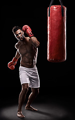 Image showing Boxing, man and training in studio with punching bag for workout, exercise or competition fight with fitness. Athlete, boxer and confidence for martial arts with energy or topless on black background