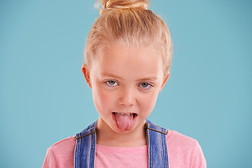 Image showing Kid, portrait and tongue out in studio for silly, goofy and playful facial expression with blue background. Child, crazy and funny face of young girl for comic gesture, humor and joking for comedy