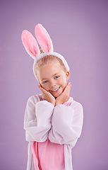 Image showing Girl, bunny and portrait with smile, studio and celebration for easter holiday. Child, costume and youth with pastel, rabbit and happy for fun cute childhood dress up isolated on purple background