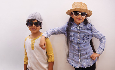 Image showing Children, portrait and fashion or sunglasses for style and looking cool on a wall or white background at home. Happy sibling, girl and boy with trendy clothes, casual and shades for fun or confidence