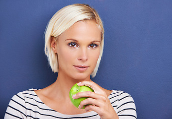 Image showing Woman, portrait and apple in studio for nutrition diet on blue background or fruit vitamin, snack or fibre. Female person, relax and wellness eating or mockup space as vegan detox, raw or lose weight