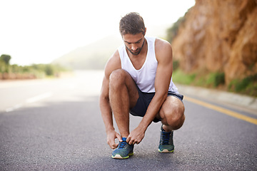 Image showing Man, runner and tying laces on road for workout, prepare and sneakers for cardio or training for marathon. Male person, feet and fitness on mountain for performance, athlete and ready for exercise