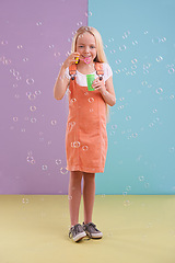 Image showing Fun, playing and girl blowing bubbles in studio with activity for child development and hobby. Youth, toy and young kid model with casual, cool and trendy style isolated by color block background.