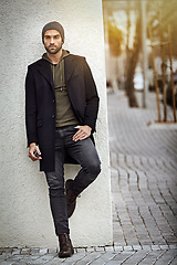 Image showing Fashion, serious or man on wall in city in casual clothes or thinking of jeans for winter outdoor. Dream, planning future or stylish person in urban street in beanie, hoodie or trendy jacket in Spain