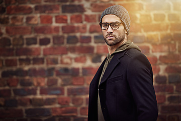 Image showing Man, portrait and urban fashion by brick wall downtown for aesthetic, modern and expression for city culture. Male person, trendy winter outfit for streetwear style for creative career in retail