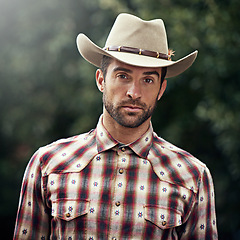 Image showing Man, portrait and outdoor cowboy outfit, western culture and countryside ranch in Texas. Male person, hat and flannel trend for farmer aesthetic, nature and plaid style by trees or outside bush