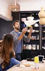 Image showing Child, dough and parents throw pizza in kitchen teaching a recipe for help, support or learning in home. Playing, cooking lesson and girl baking with family, dad and mom for dinner, supper or lunch