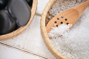 Image showing Basket, stone and salt closeup in spa for luxury service in hospitality at hotel on holiday or vacation. Rocks, container and object for wellness treatment on table with detail of pebble or minerals