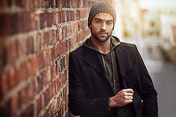 Image showing Man, portrait and winter fashion by brick wall downtown for aesthetic, modern and vacation for city culture. Male person, trendy urban outfit for streetwear style for creative career in New York