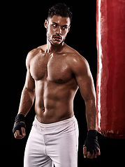 Image showing Punching bag, man and boxing with fitness, training for a competition and wellness on a dark studio background. Person, model and guy with exercise and strong with workout and muscular with cardio