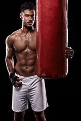 Image showing Portrait, body and fitness man with punching bag in studio for training, challenge or power performance on black background. Face, chest and male fighter at gym for wellness, resilience or workout