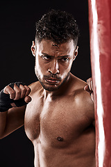 Image showing Boxing, man and training in studio with fitness for workout, exercise or competition fight with punching bag. Athlete, boxer and confidence for martial arts with energy or topless on black background