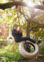 Image showing Boy, child and tyre swing with portrait in garden with smile, playing and countryside vacation in summer. Kid, face and diy adventure playground in backyard of home with sunlight and trees in nature