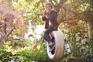 Image showing Boy, tyre swing and portrait in garden with happiness, playing and countryside vacation in summer. Child, face and diy adventure playground in backyard of home with sunlight, trees or smile in nature