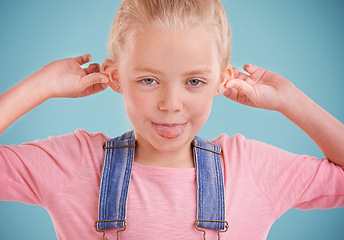 Image showing Child, portrait and tongue out in studio for goofy, silly and playful facial expression with blue background. Happy, crazy and funny face of young girl for comic, humor and joking for comedy