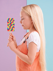 Image showing Studio, girl and decision with lollipop, dessert and choice for snack and childhood. Child, sweets and yummy selection for tasty, eating and choosing on vibrant split pastel pink and blue background