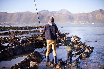 Image showing Man, kid and beach for fishing in winter as hobby with bonding for child development, growth and life skills in Australia. Dad, boy and stand in rocks at coast for family tradition, memory and care