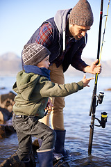 Image showing Father, fishing and teaching for young boy, rocks and bonding for activity by ocean. Sea, rod and learning how to fish for childhood development, winter and hobby together while on seaside vacation