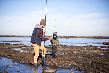 Image showing Father, boy and fishing at sea in winter as hobby with bonding for child development, learning and growth in Australia. Dad, kid and stand in boulders at coast for family tradition, memory and care